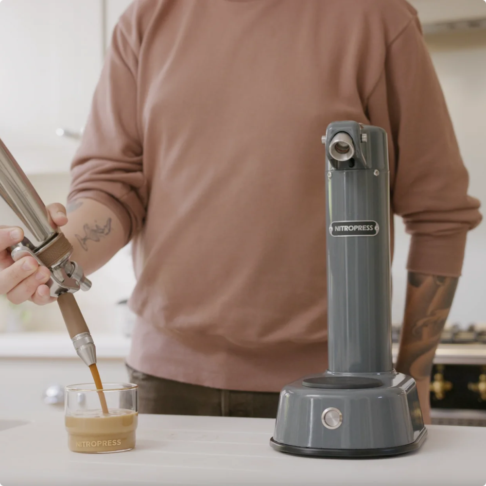 Person using a NitroPress coffee machine to make a coffee drink.